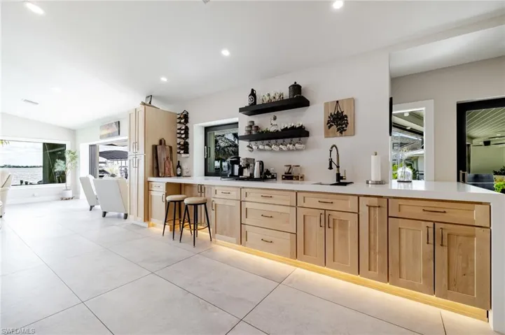 Bar featuring light wood finish cabinets, open shelves, recessed lighting, light stone countertops, and light tile patterned flooring