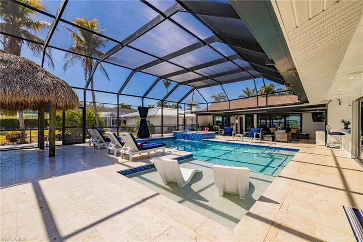 Combined pool / hot tub with a lanai, a patio area, a sunroom, and outdoor seating