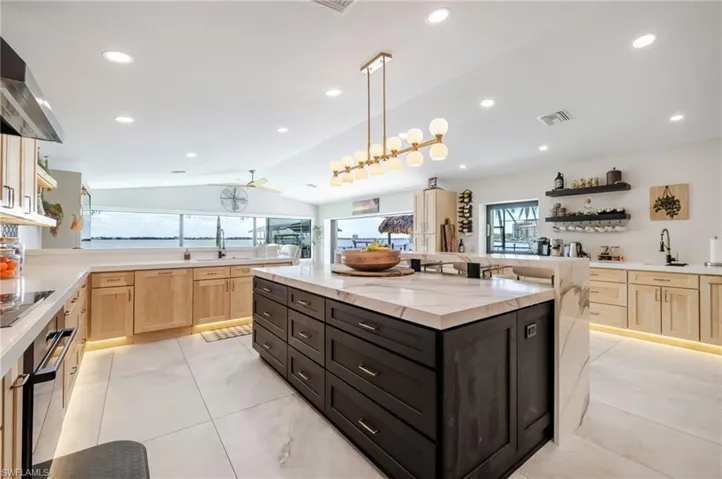 Two tone kitchen featuring open shelves, two tone cabinetry, a kitchen island, oven, and black electric cooktop