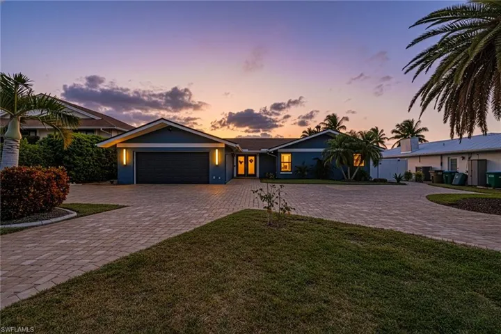 Ranch-style house featuring curved driveway, a yard, stucco siding, and an attached garage