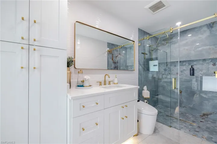 Bathroom with vanity, a shower stall, and tile walls