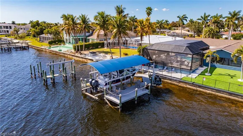 Dock area featuring boat lift, glass enclosure, a water view, and an outdoor pool