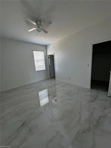 Empty room with light marble finish floors and ceiling fan