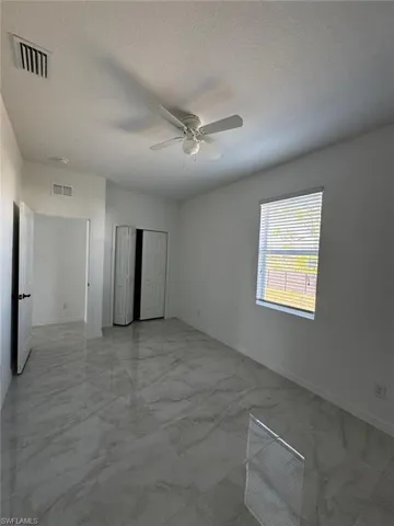 Unfurnished bedroom featuring light marble finish floors, a textured ceiling, a ceiling fan, and a closet