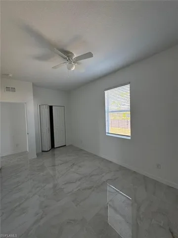 Unfurnished bedroom with light marble finish flooring, a textured ceiling, a ceiling fan, and a closet