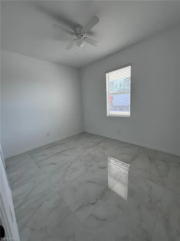 Spare room with light marble finish flooring and ceiling fan