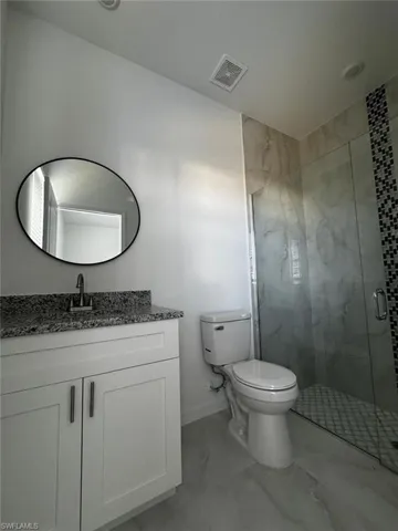 Full bathroom featuring a stall shower, light marble finish floors, and vanity