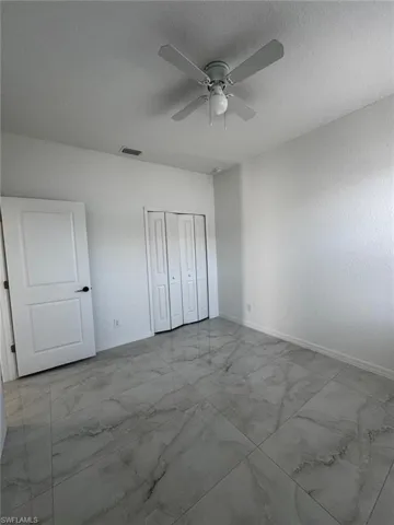 Unfurnished bedroom with light marble finish flooring, ceiling fan, a closet, and a textured ceiling