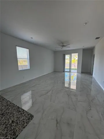 Unfurnished room featuring light marble finish flooring, plenty of natural light, and ceiling fan