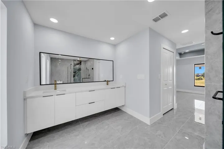 Contemporary bathroom featuring a floating dual vanity with white cabinetry, quartz countertop, and a full-width mirror