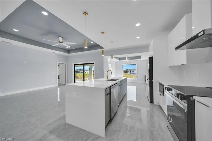 Sleek kitchen island with a white countertop and integrated sink, complemented by gold-finish pendant lighting and a matching faucet