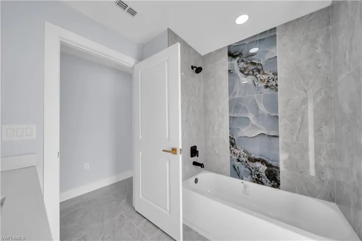 Bathtub with a unique, contrasting tile inlay and matte black fixtures