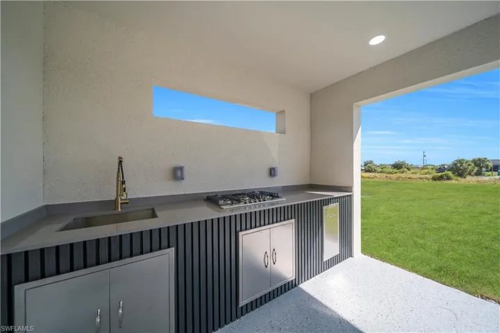Outdoor kitchen featuring a built-in gas cooktop, stainless steel sink with a modern faucet, and integrated cabinetry