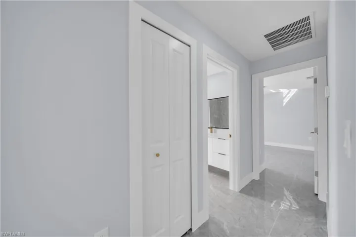 Hallway featuring light blue walls, grey stone-finish flooring, and white trim