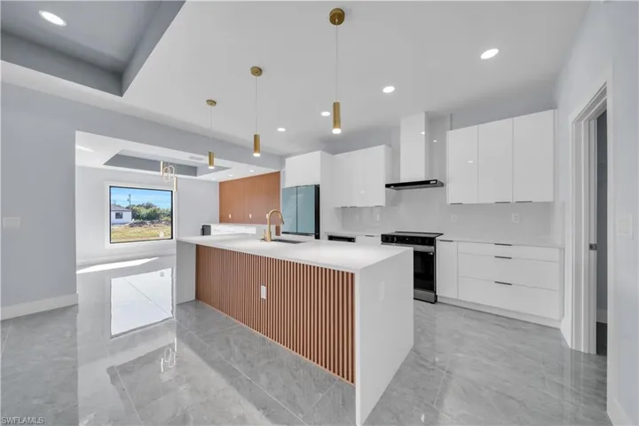 Contemporary kitchen featuring a large island with slat-wood paneling, white countertops, and gold-finish pendant lighting