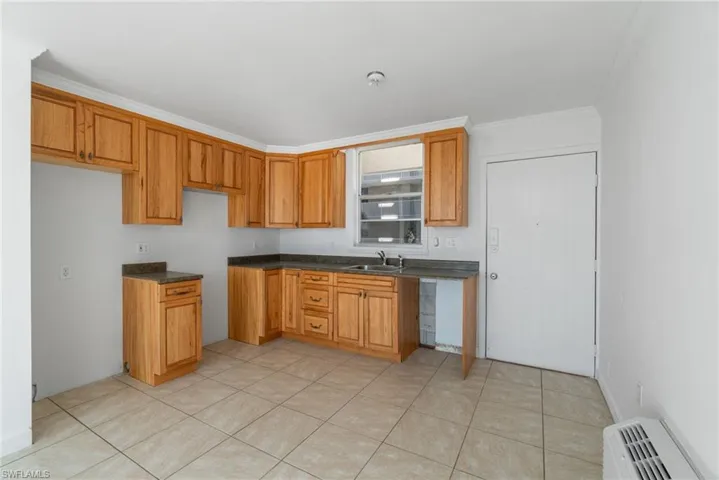 Kitchen with dark countertops, ornamental molding, brown cabinets, and a wall mounted AC