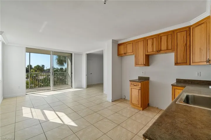 Kitchen featuring a wall of windows, dark countertops, brown cabinetry, light tile patterned flooring, and crown molding