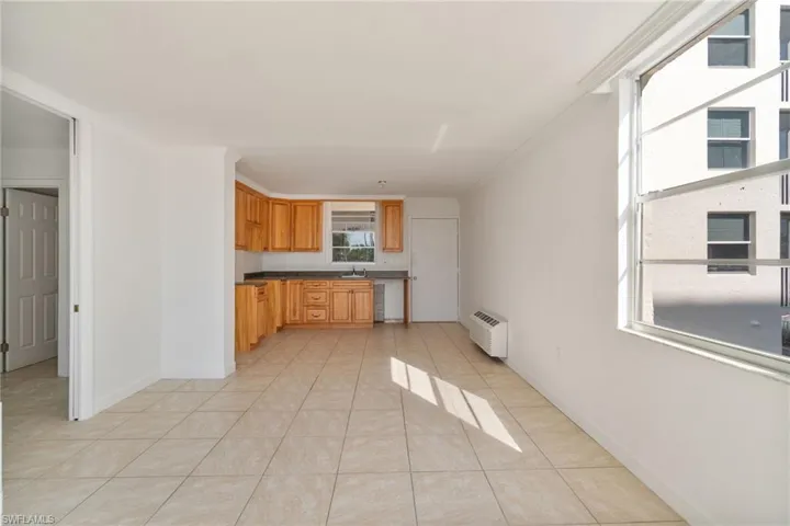 Kitchen with dark countertops, light tile patterned flooring, and a wall mounted AC