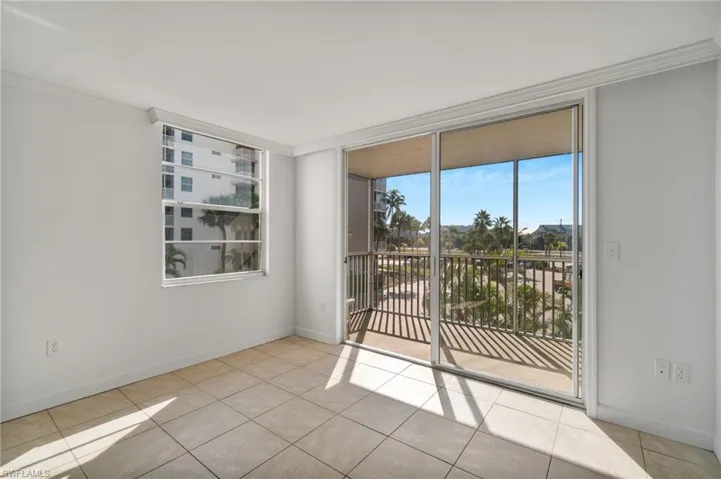 Spare room featuring crown molding, a wall of windows, and light tile patterned floors