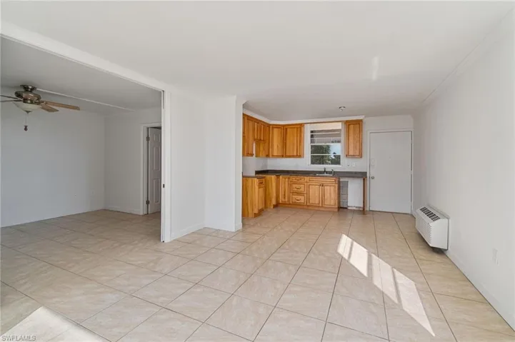 Kitchen with dark countertops, a ceiling fan, light tile patterned floors, and a wall mounted air conditioner