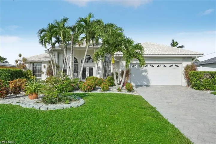 View of front of home with a front yard, concrete driveway, stucco siding, a tiled roof, and a garage