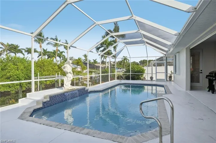 Outdoor pool with glass enclosure, area for grilling, and a patio area