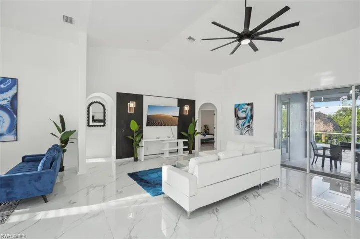 Living area with arched walkways, marble finish floor, ceiling fan, and visible vents