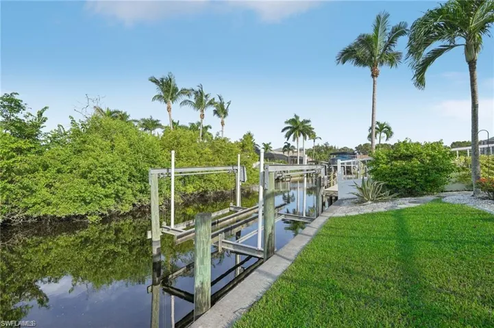 Dock area featuring a water view, boat lift, and a yard