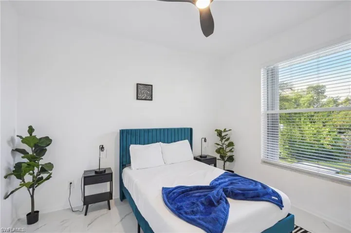 Bedroom featuring baseboards, marble finish floor, and a ceiling fan