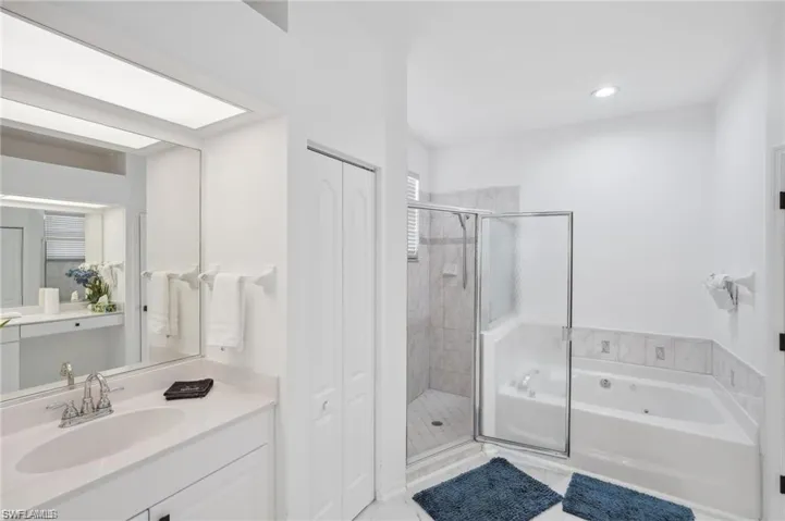 Bathroom with a stall shower, recessed lighting, vanity, and a garden tub