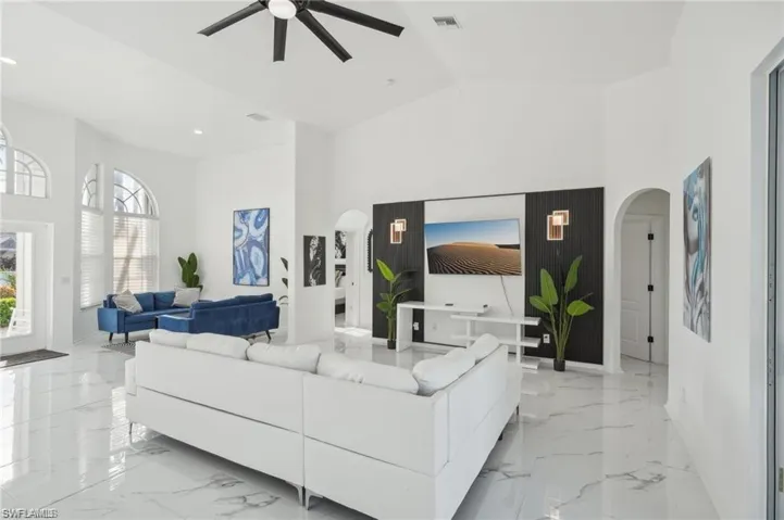 Living area with marble finish floor, visible vents, arched walkways, and a ceiling fan
