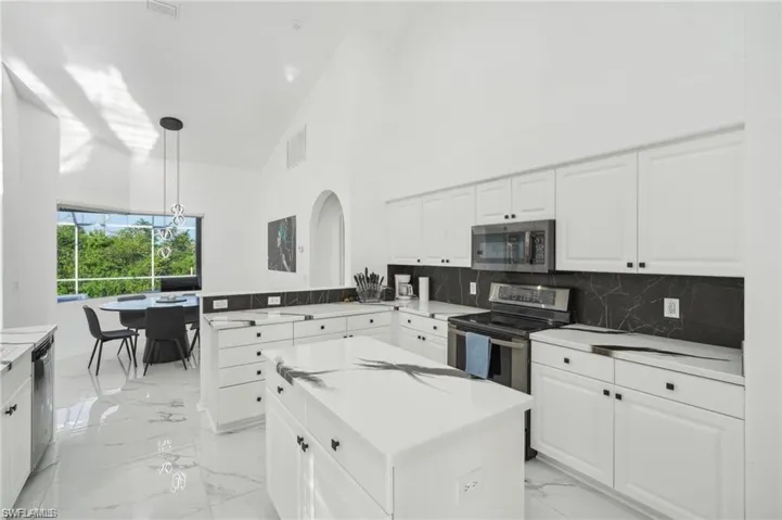 Kitchen with visible vents, a peninsula, marble finish floor, stainless steel appliances, and white cabinetry