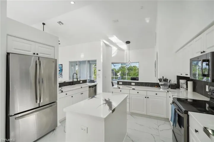 Kitchen with marble finish floor, a sink, a peninsula, and appliances with stainless steel finishes