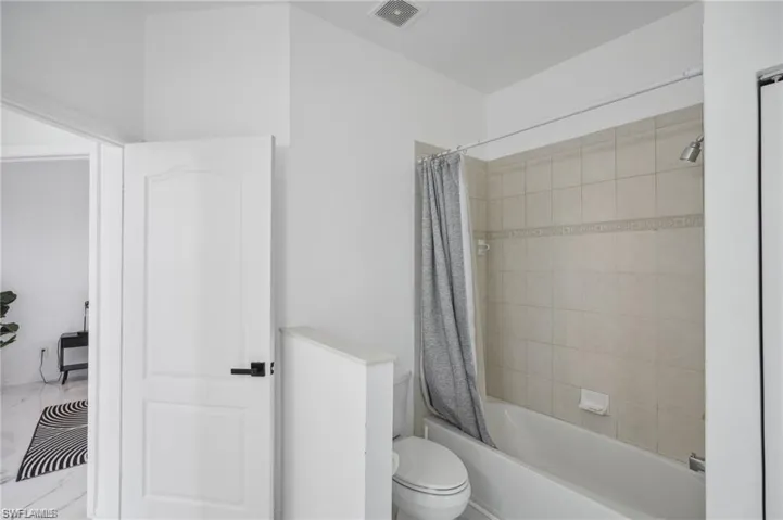 Full bathroom featuring visible vents, toilet, and shower / tub combo