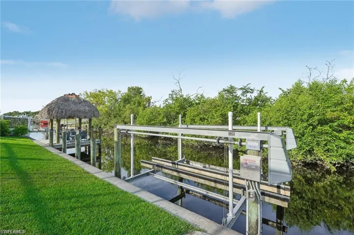 View of dock featuring a lawn and boat lift