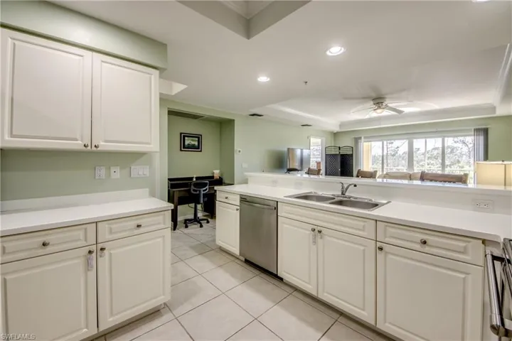 Kitchen featuring appliances with stainless steel finishes, a raised ceiling, ceiling fan, sink, and light tile patterned flooring