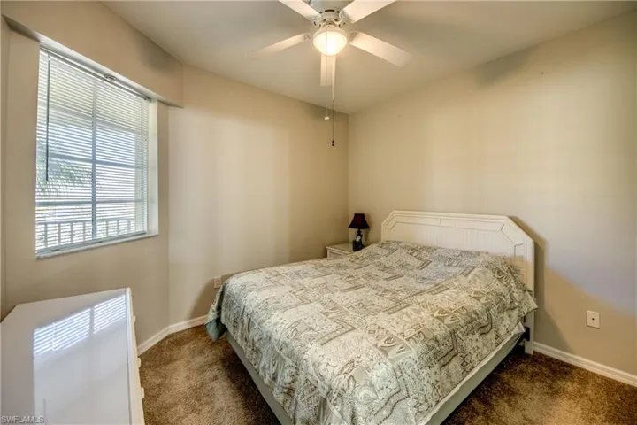 Bedroom featuring ceiling fan and dark carpet