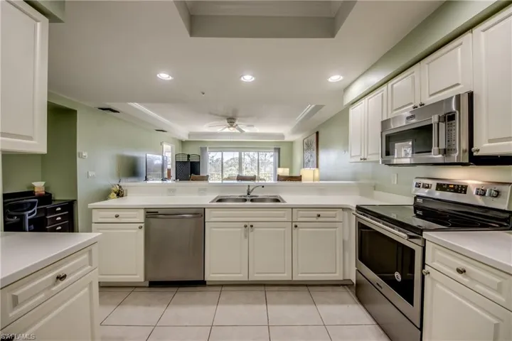 Kitchen with white cabinets, a raised ceiling, sink, and appliances with stainless steel finishes