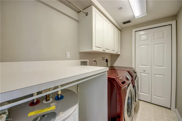 Washroom with cabinets, separate washer and dryer, and water heater