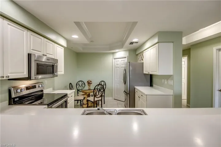 Kitchen with a tray ceiling, white cabinetry, sink, and stainless steel appliances