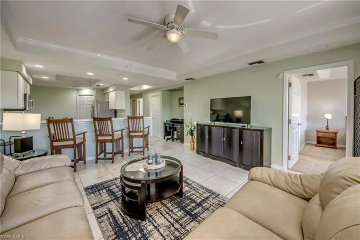 Tiled living room with ceiling fan and ornamental molding