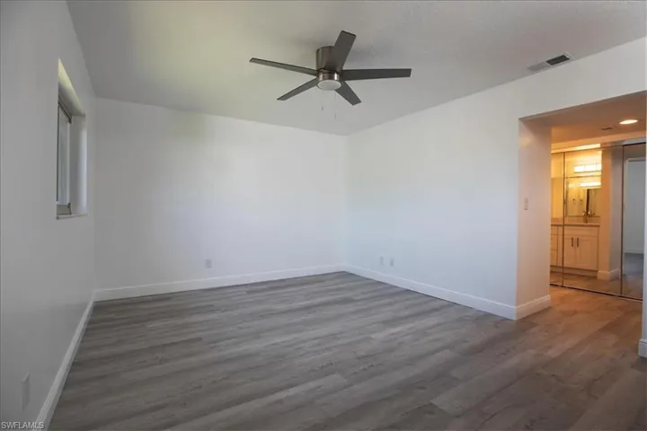 Unfurnished room with ceiling fan and dark wood-type flooring