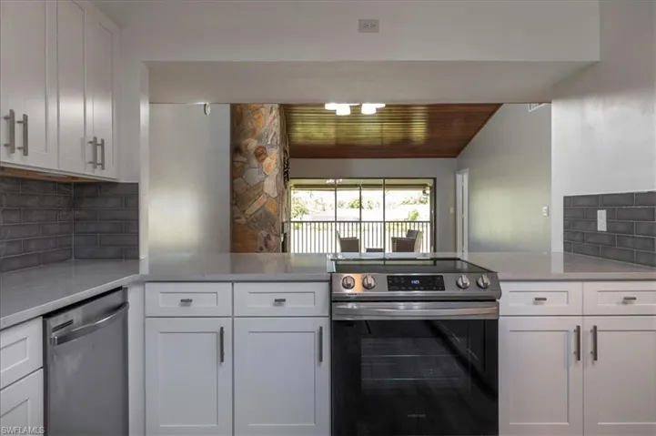 Kitchen with white cabinets, appliances with stainless steel finishes, decorative backsplash, and wood ceiling