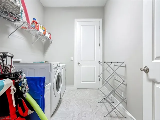 Washroom featuring washing machine and clothes dryer and baseboards