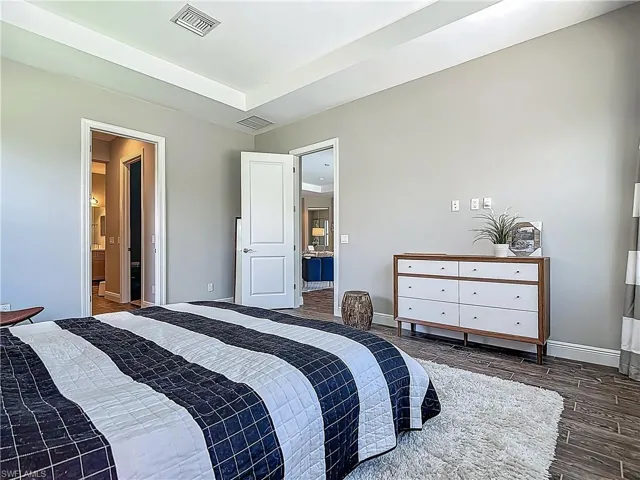 Bedroom featuring baseboards, wood finished floors, and connected bathroom