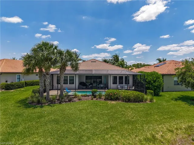 Back of house with a yard, a tiled roof, an outdoor pool, and a patio