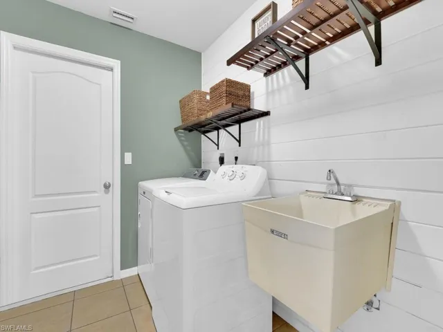 Washroom featuring light tile patterned flooring and washer and dryer