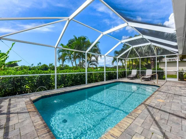 Swimming pool with glass enclosure, a sunroom, and a patio