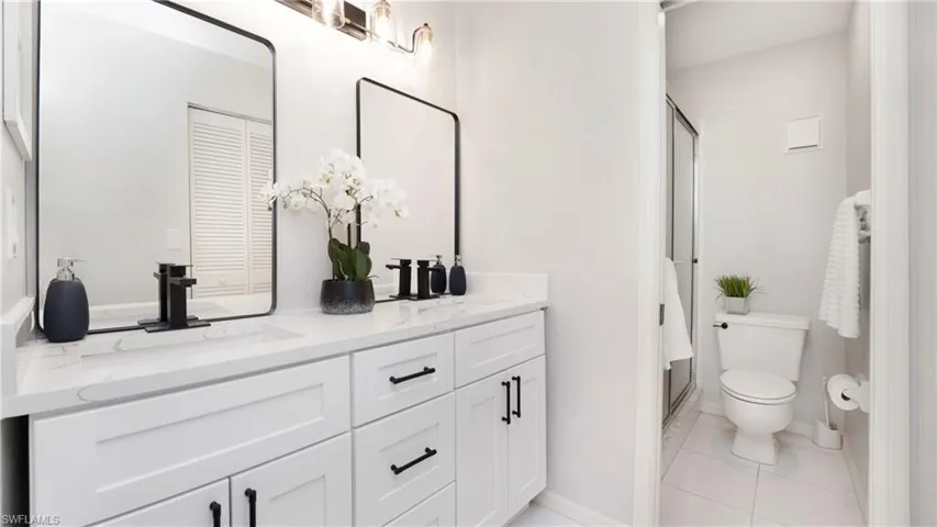 Full bath featuring a stall shower, double vanity, and light tile patterned floors