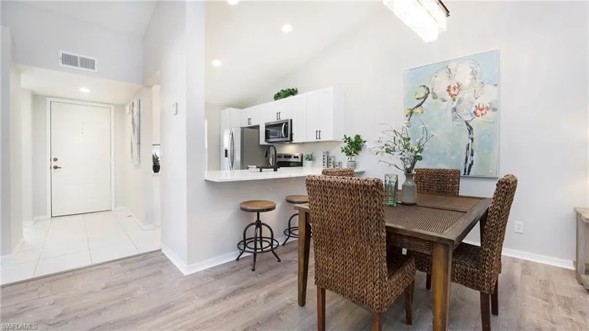 Dining space with high vaulted ceiling, light wood-type flooring, and recessed lighting